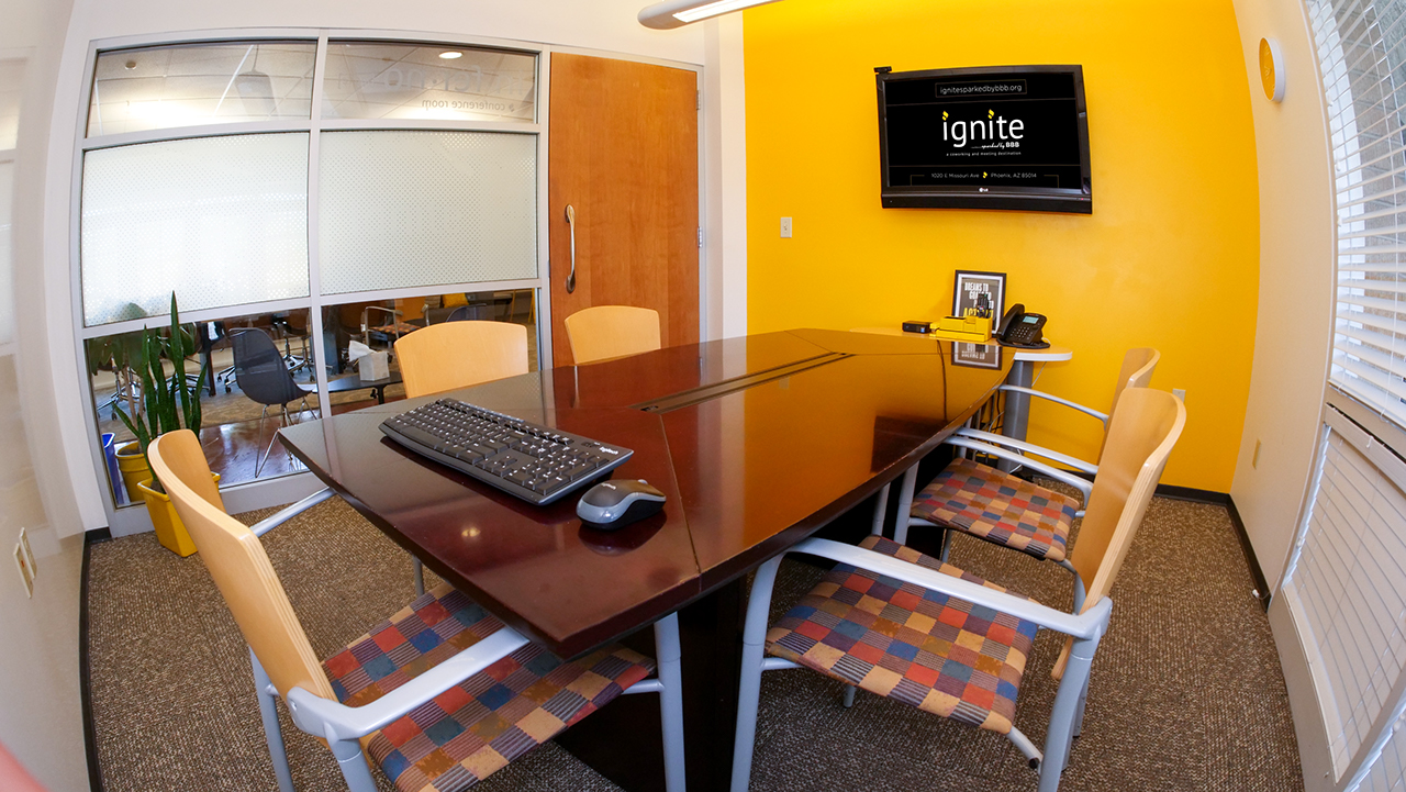 small room with rectangle table and a tv on a yellow wall with floor to ceiling windows