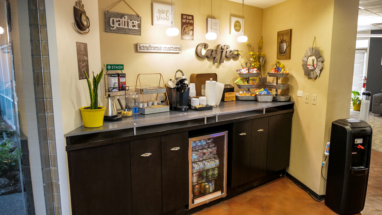 counter with snacks and mini fridge with water and soft drinks, decorated with welcoming wall hangings