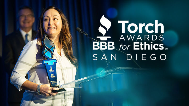 Female business owner holding Torch Awards trophy at podium