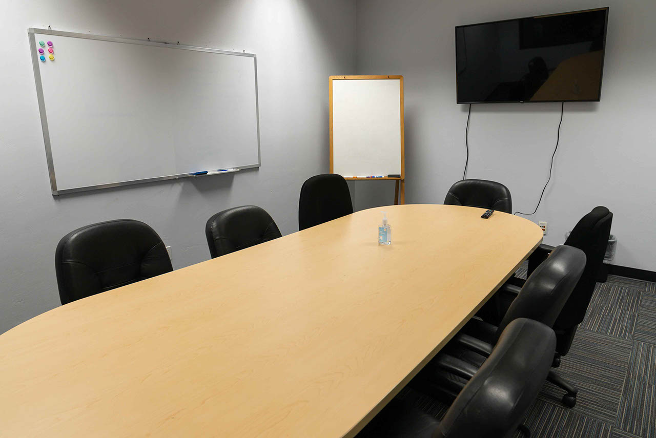 Room with large table, chairs, whiteboards and large mounted tv, Butte conference room