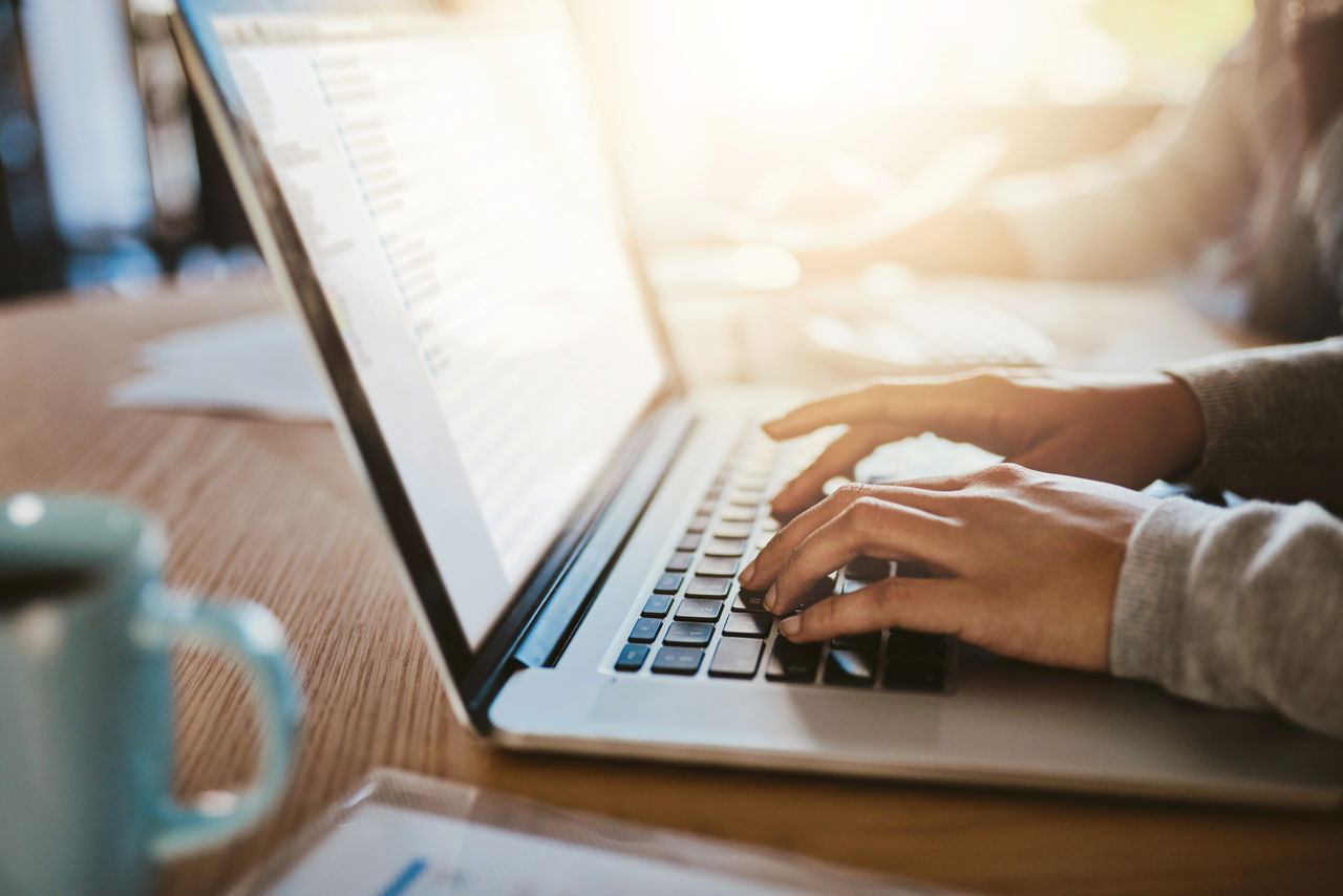 Closeup shot of an unrecognizable woman using a laptop with her husband in the background