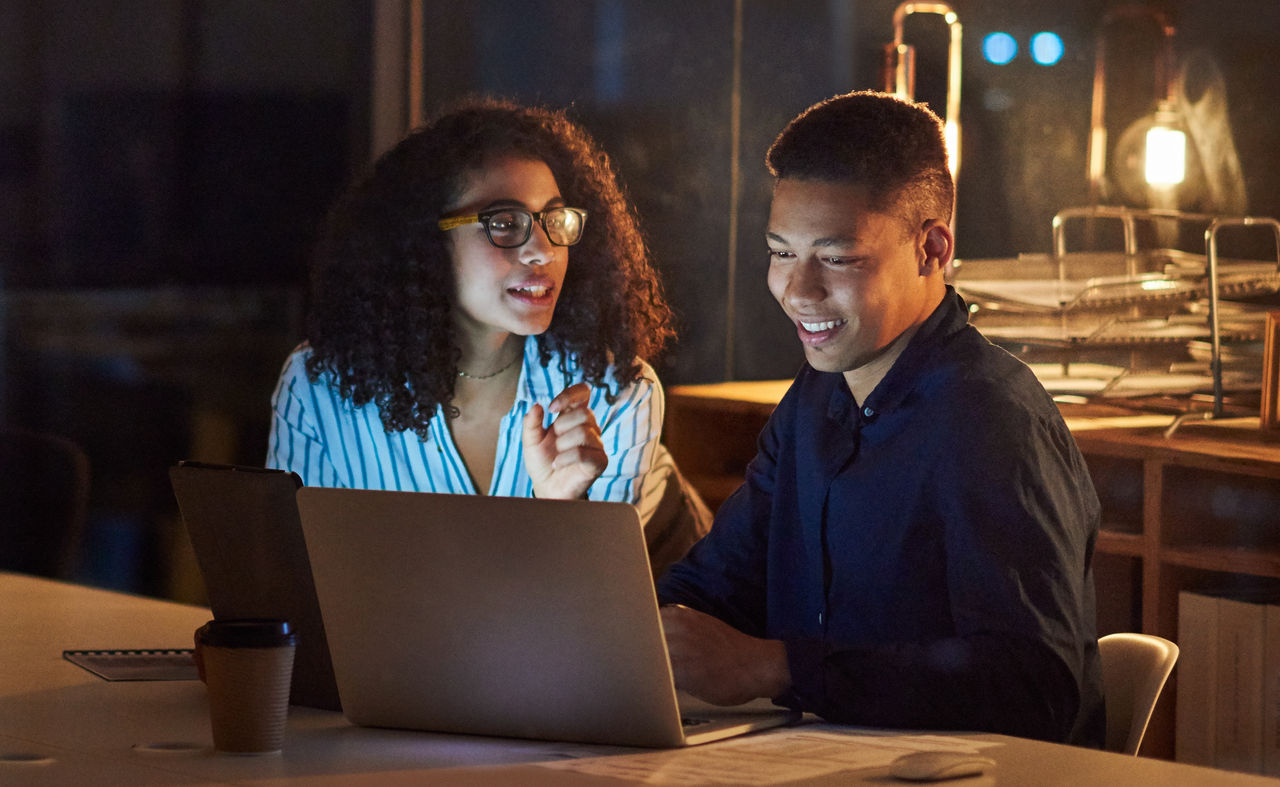 Shot of a young businessman and businesswoman using a laptop during a late night at work
