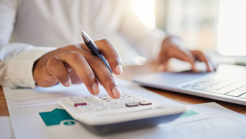 1432903655 Finance, accounting and fintech, a man on a computer and calculator working out his business budget strategy. Businessman at his office desk, laptop, money management and financial investment online.
